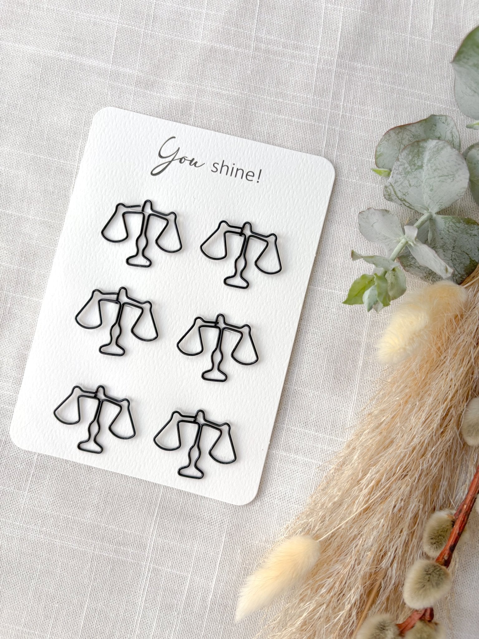 Sechs Jura Büroklammern in Waagenform auf Din A6 Karte mit dem Text "you shine"