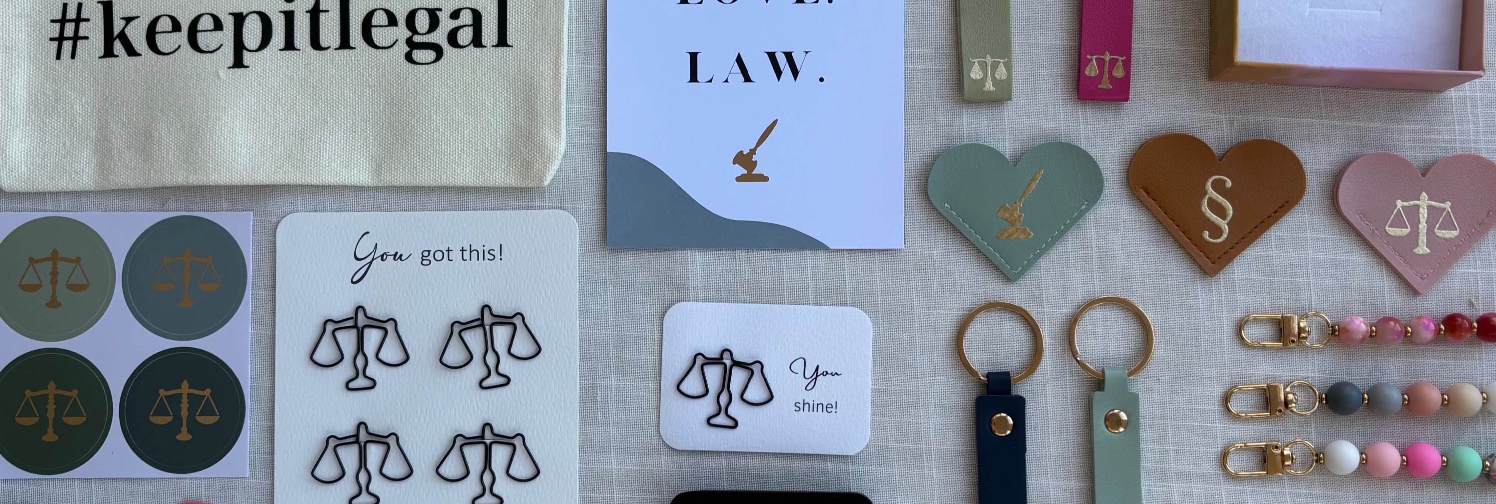 Übersicht einiger Produkte z.B. Jura Postkarten, Juristische Schlüsselanhänger, Büroklammern in Waageform, Sticker